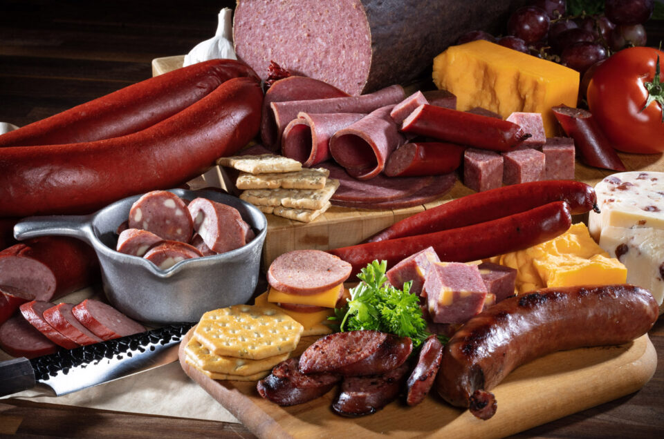 A board filled with sliced meat, cheese, and biscuits.