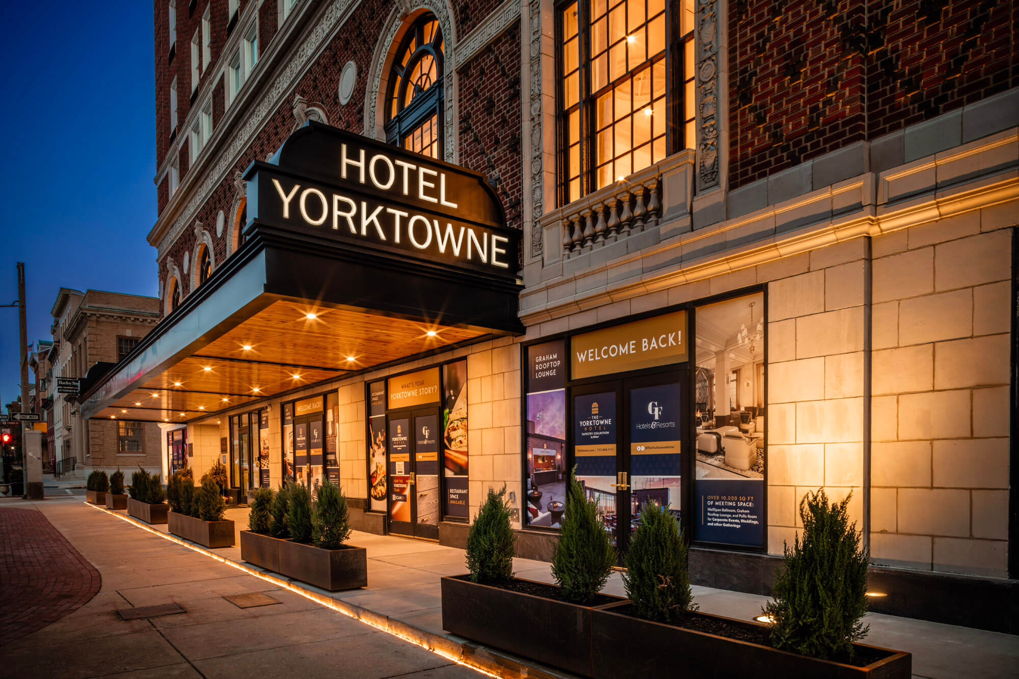 A twilight shot of the front entrance to the Yorktowne hotel with the large sign in the foreground.