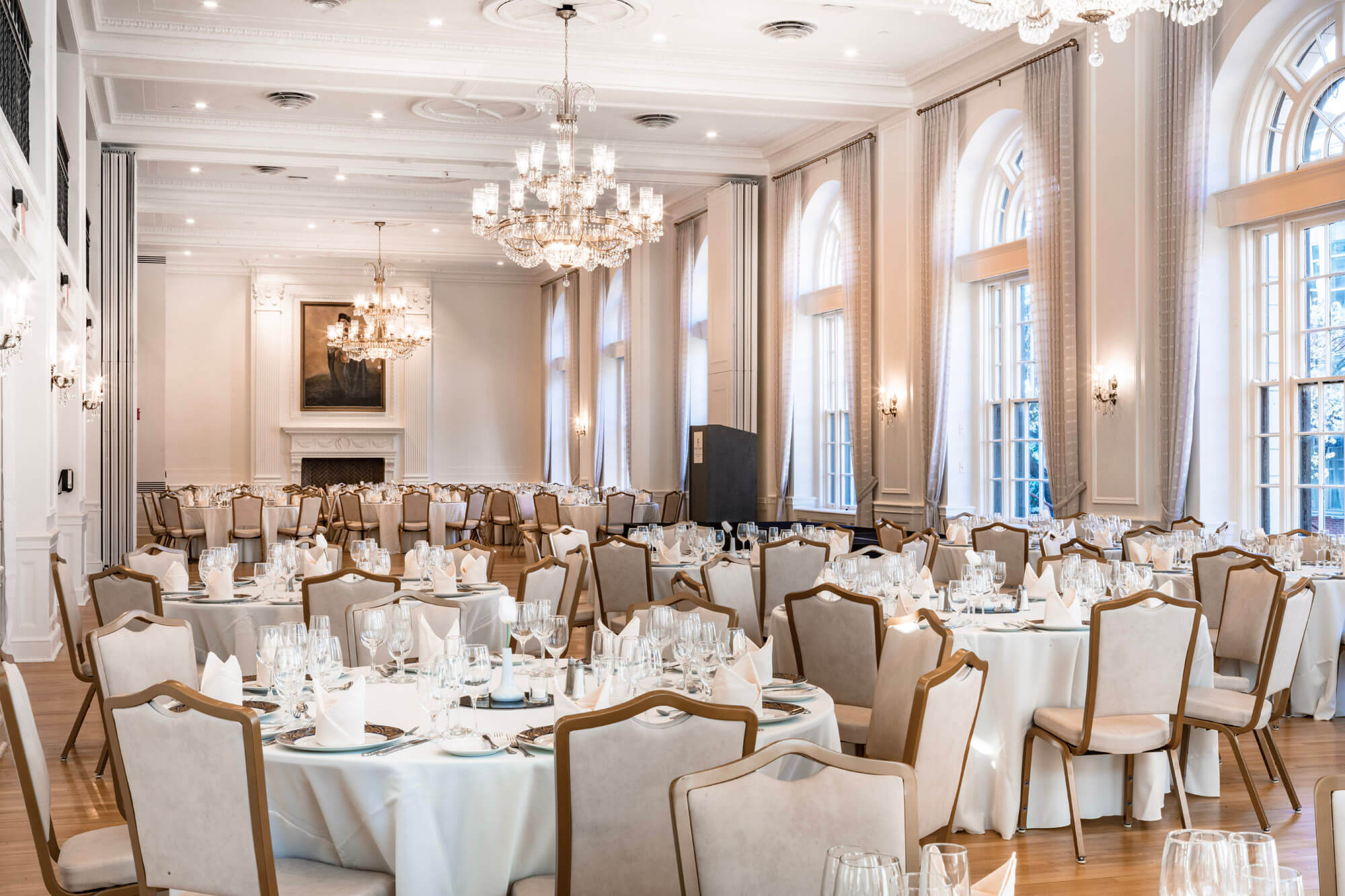 The ballroom at the Yorktowne with chandeliers, floor to ceiling windows, and many tables all set for an event.