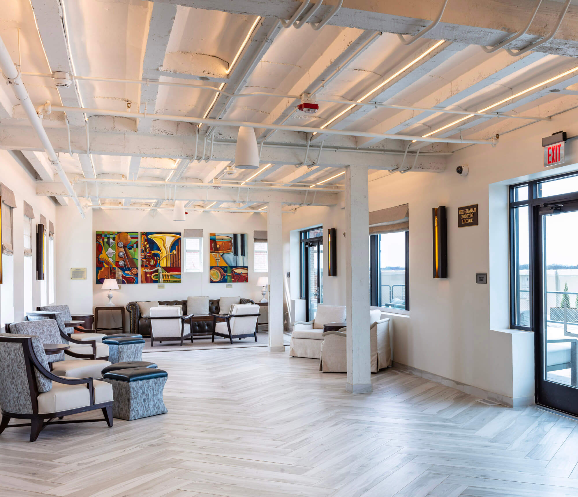 A vast room with industrial style white ceiling and chairs at the end of the room.