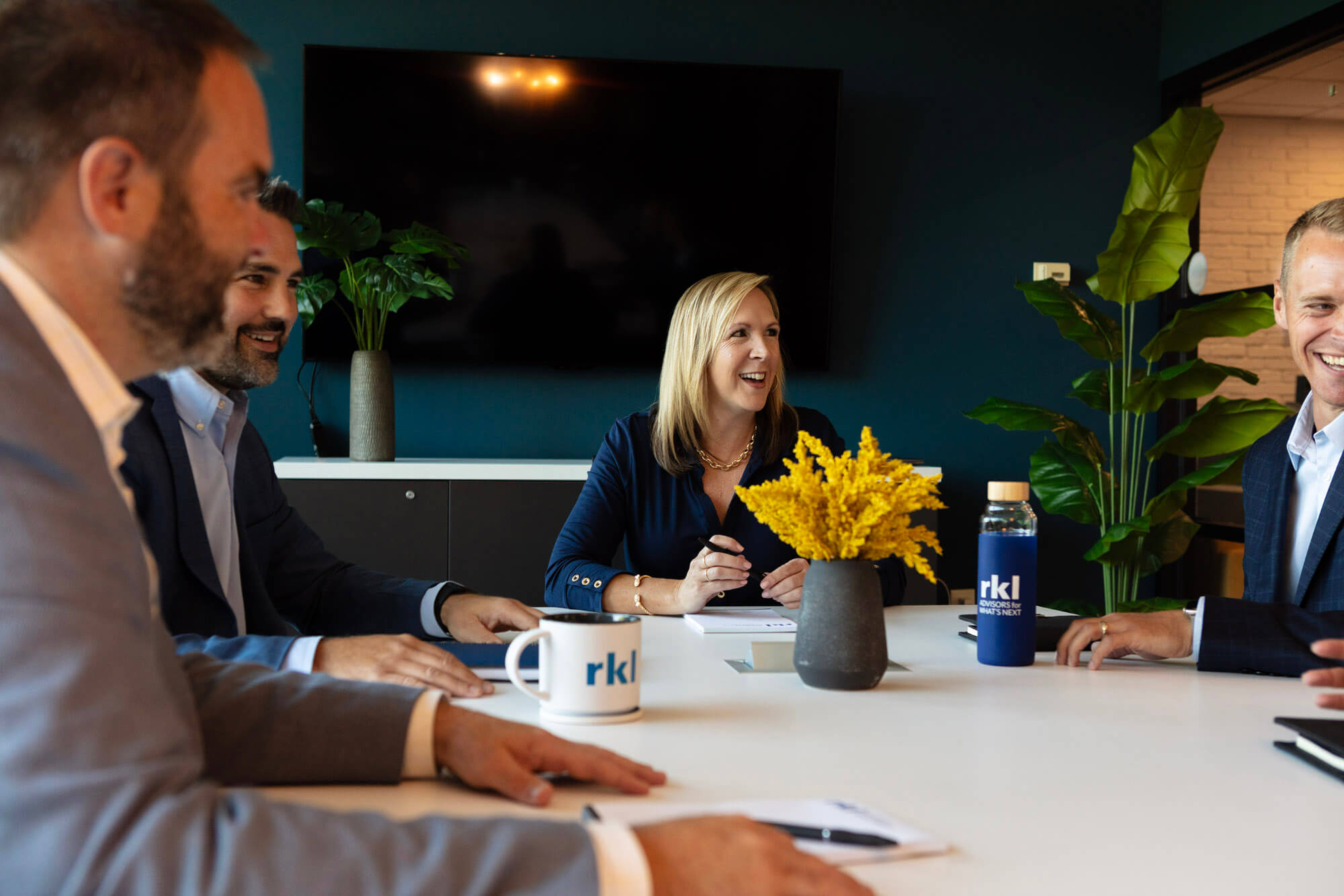 A group of colleagues meeting around a desk with notes and coffee mugs.