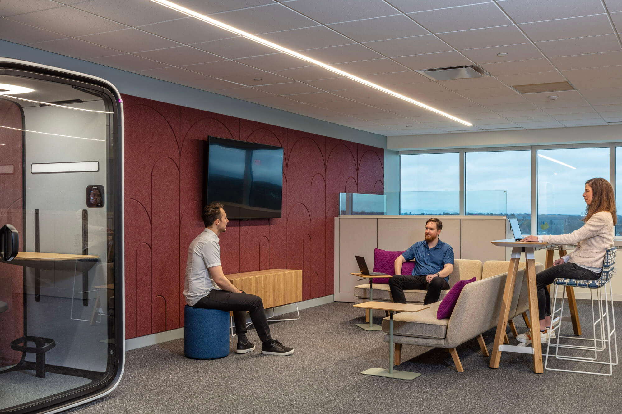 Three employees sitting in an open office meeting area.