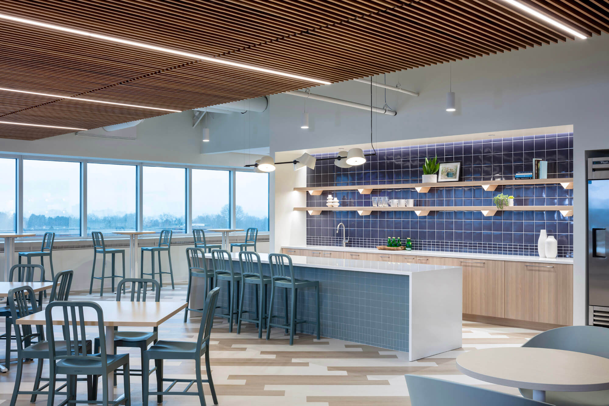 A view of the kitchen in the open planned office space with a counter and tables and chairs.