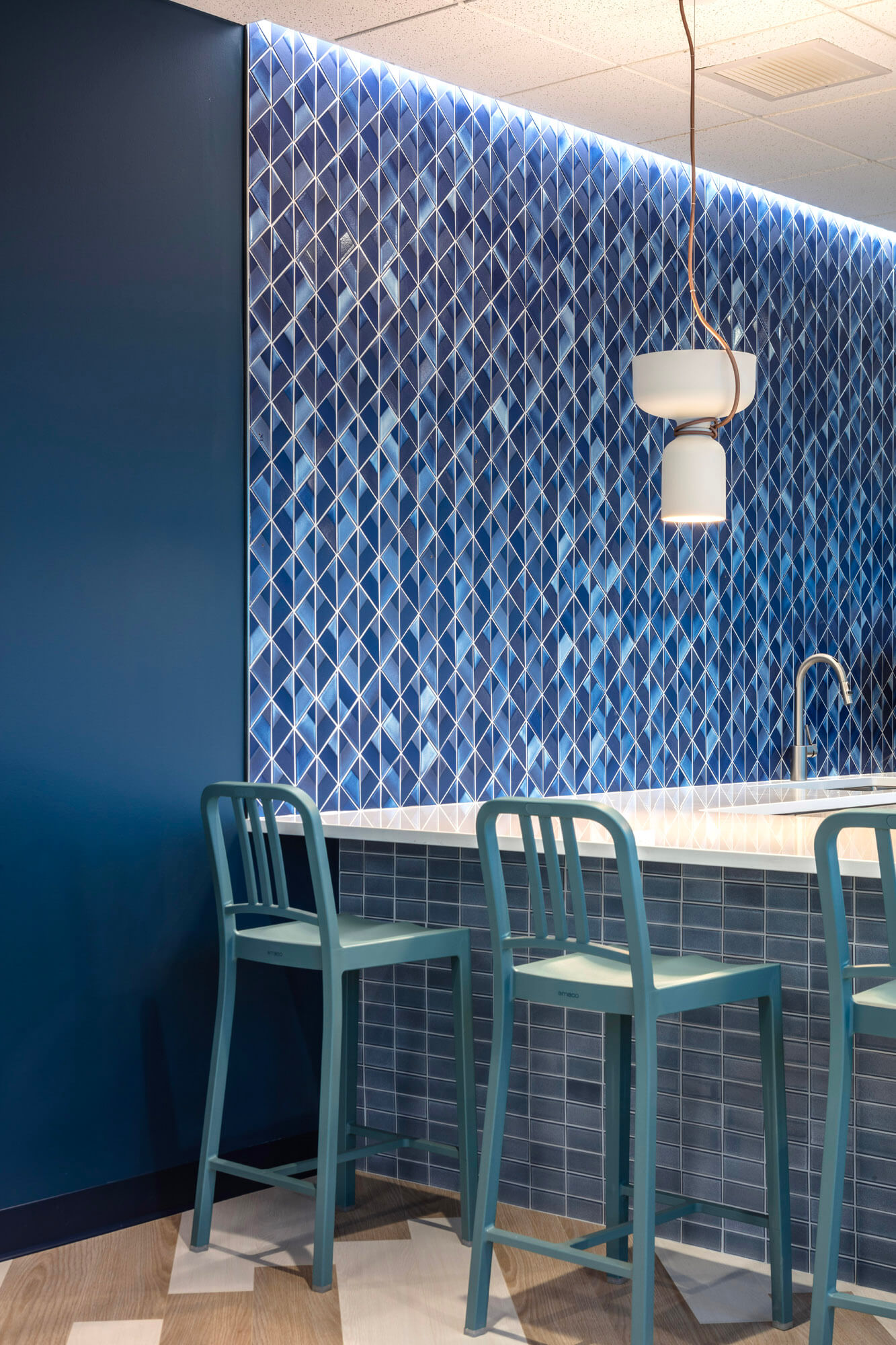 Close up image of the blue tiles kitchen with bar stools.