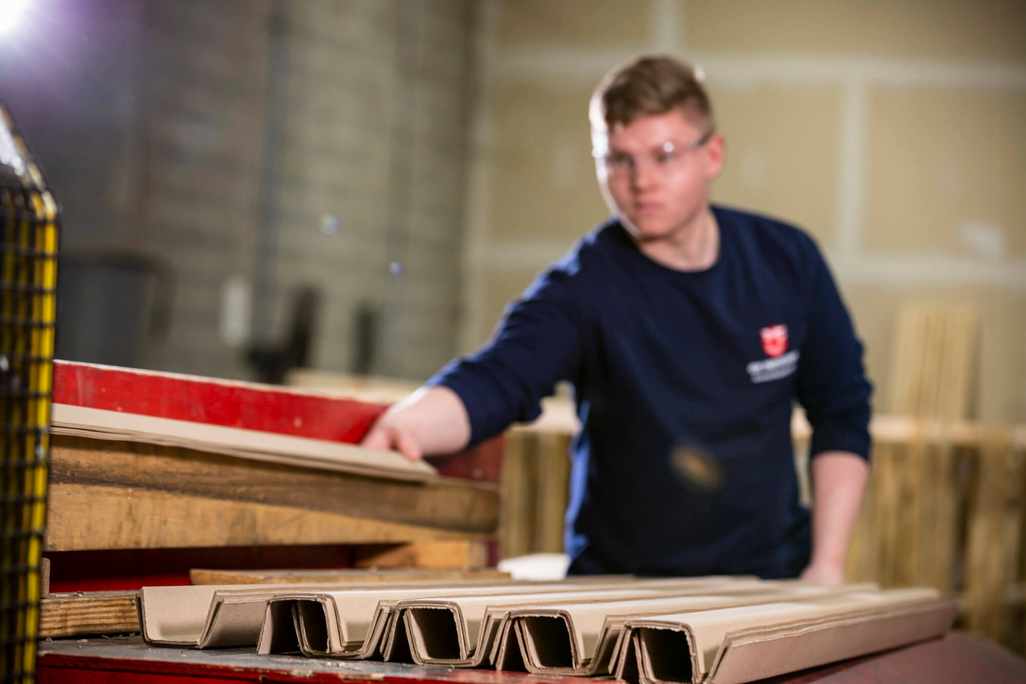 A man in the background who is placing carboard edges onto a table.