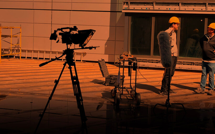 A group of four people discussing shots wearing safety gear with the filming set up beside them.