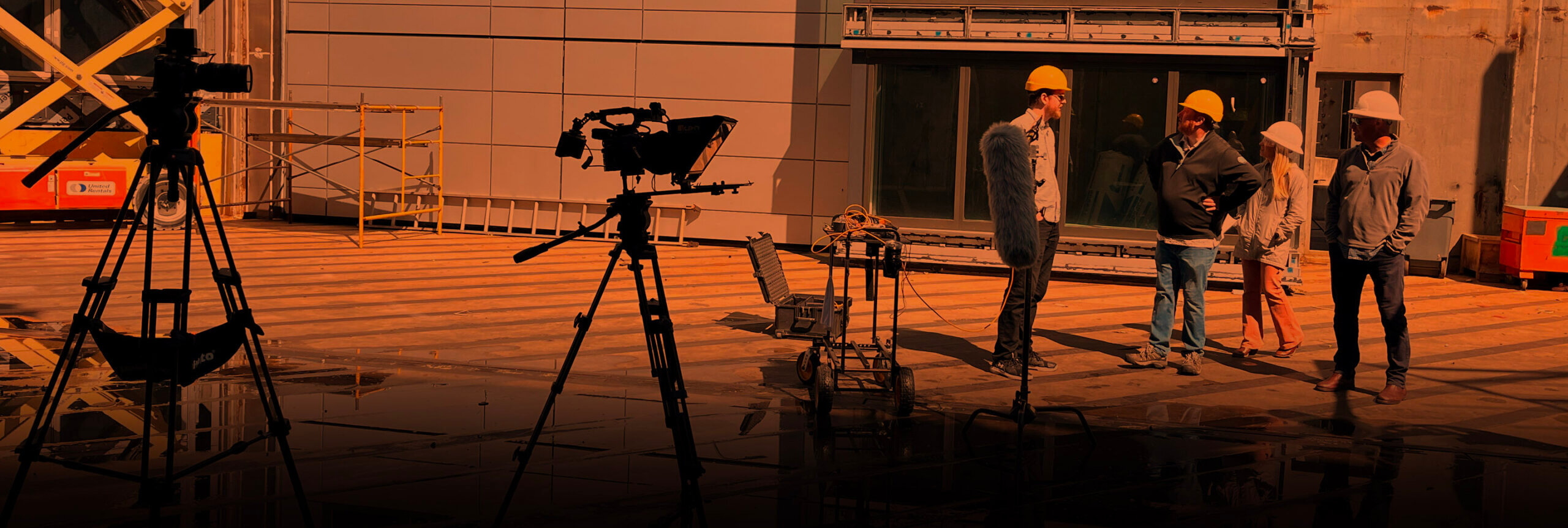 A group of four people discussing shots wearing safety gear with the filming set up beside them.