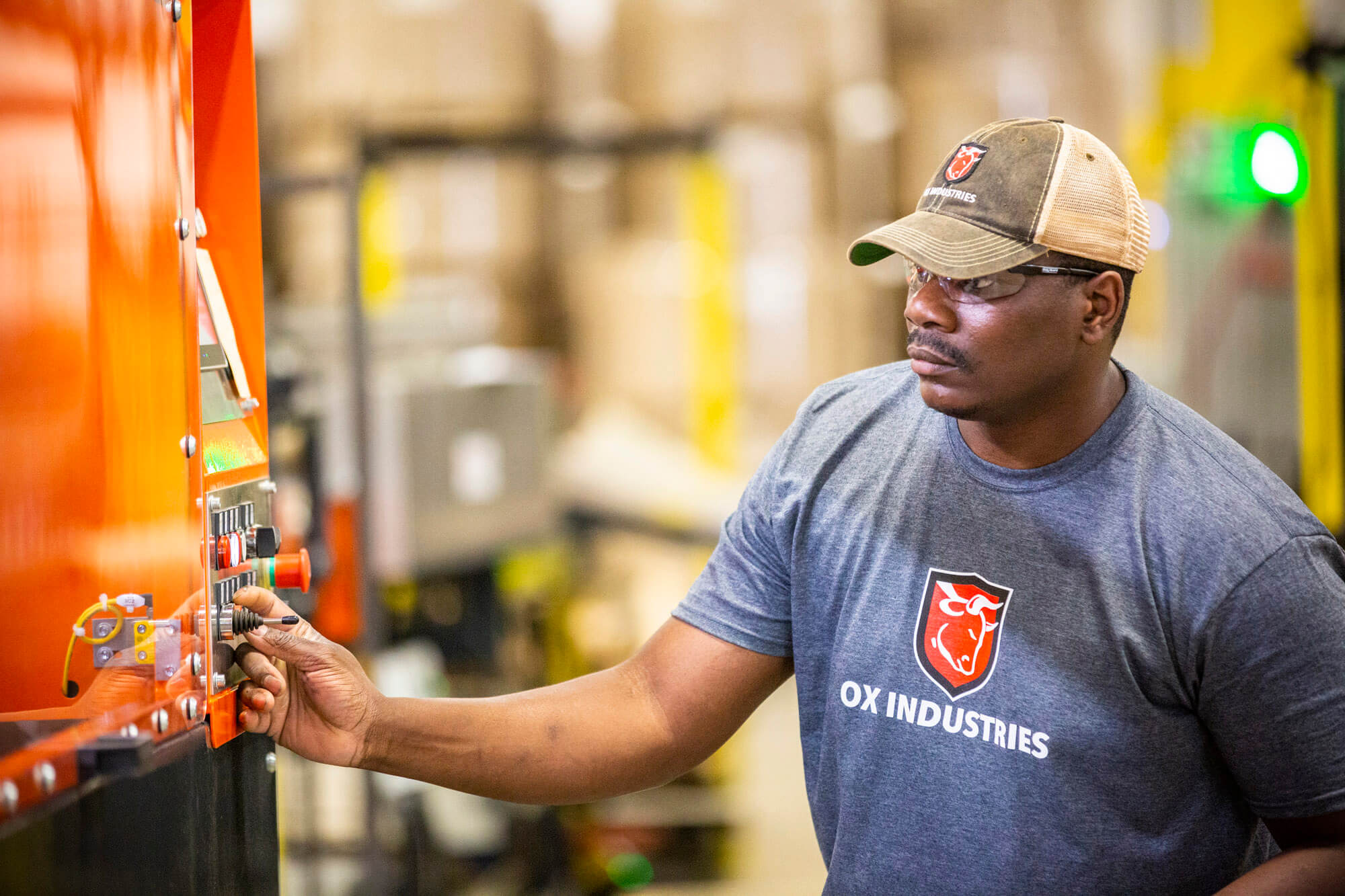 A man with an ox industries shirt on operating an orange machine.