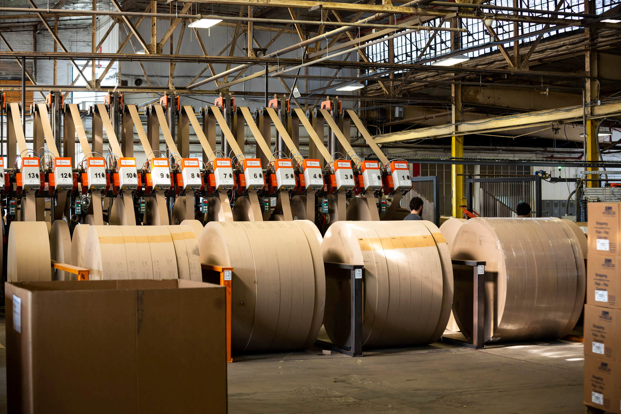 Large rolls of cardboard and a machine inside a factory.