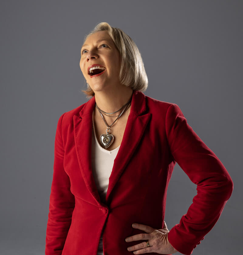 Woman in a red jacket looking up and laughing.