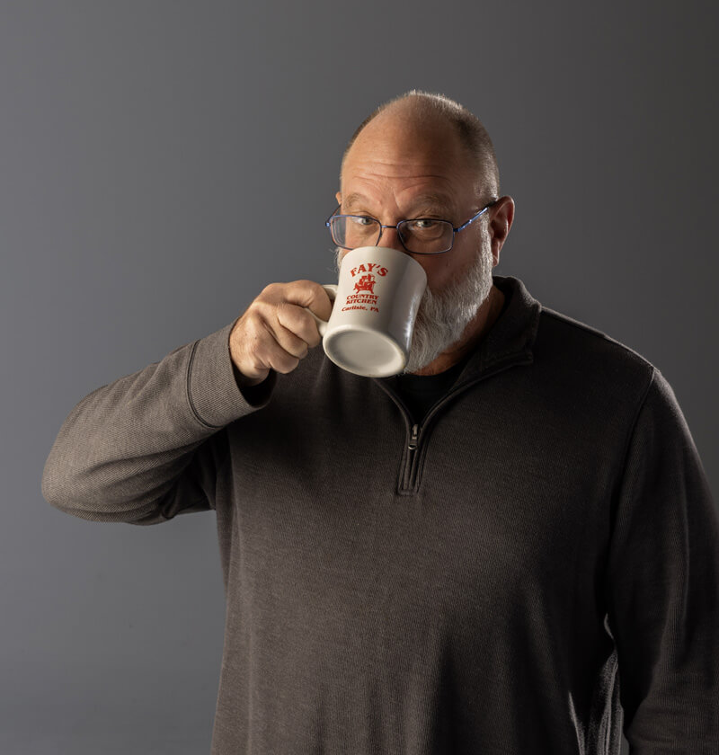 Man looking at the camera while drinking a cup of coffee.