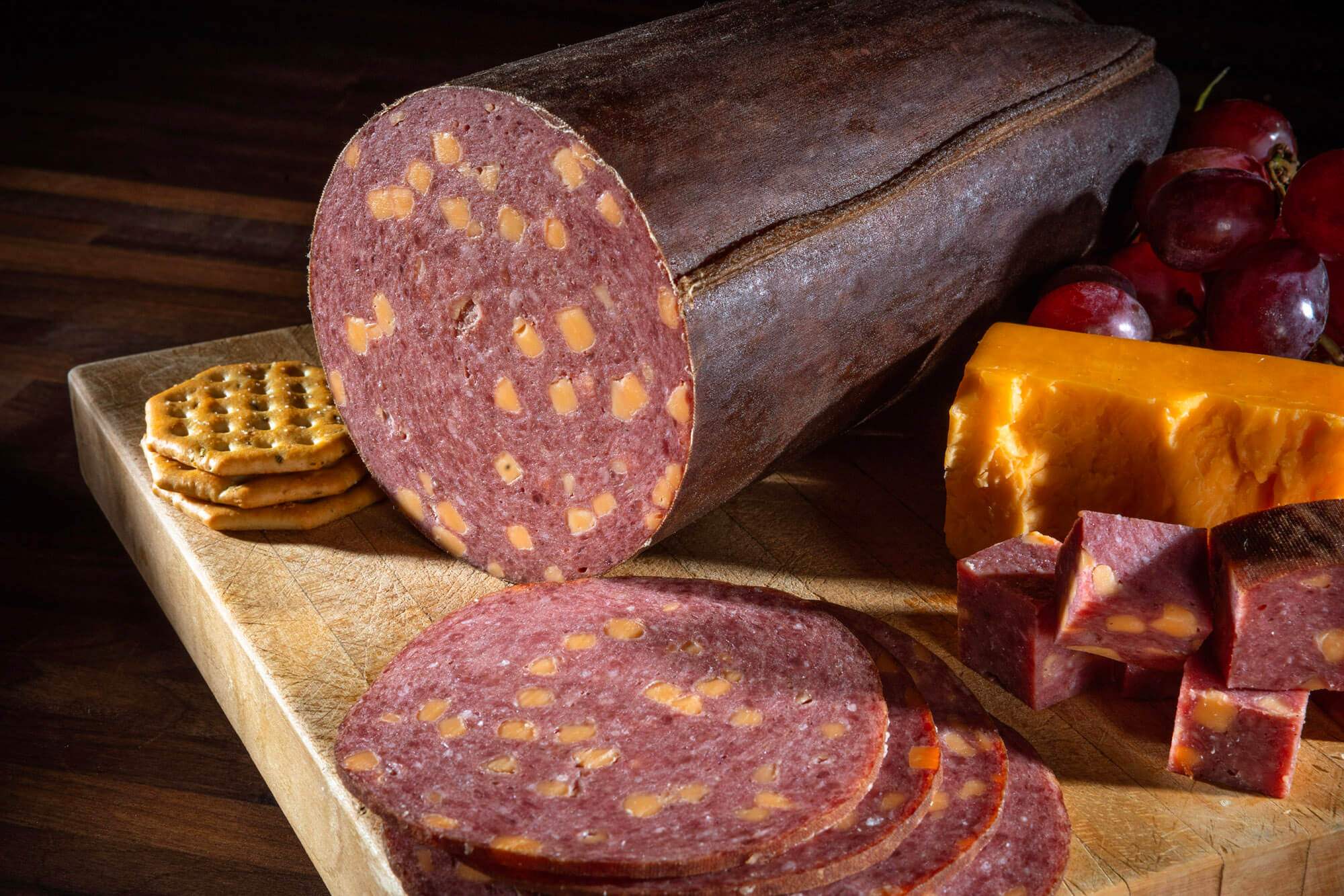 Bologna with cheese cut into slices and displayed on a board.