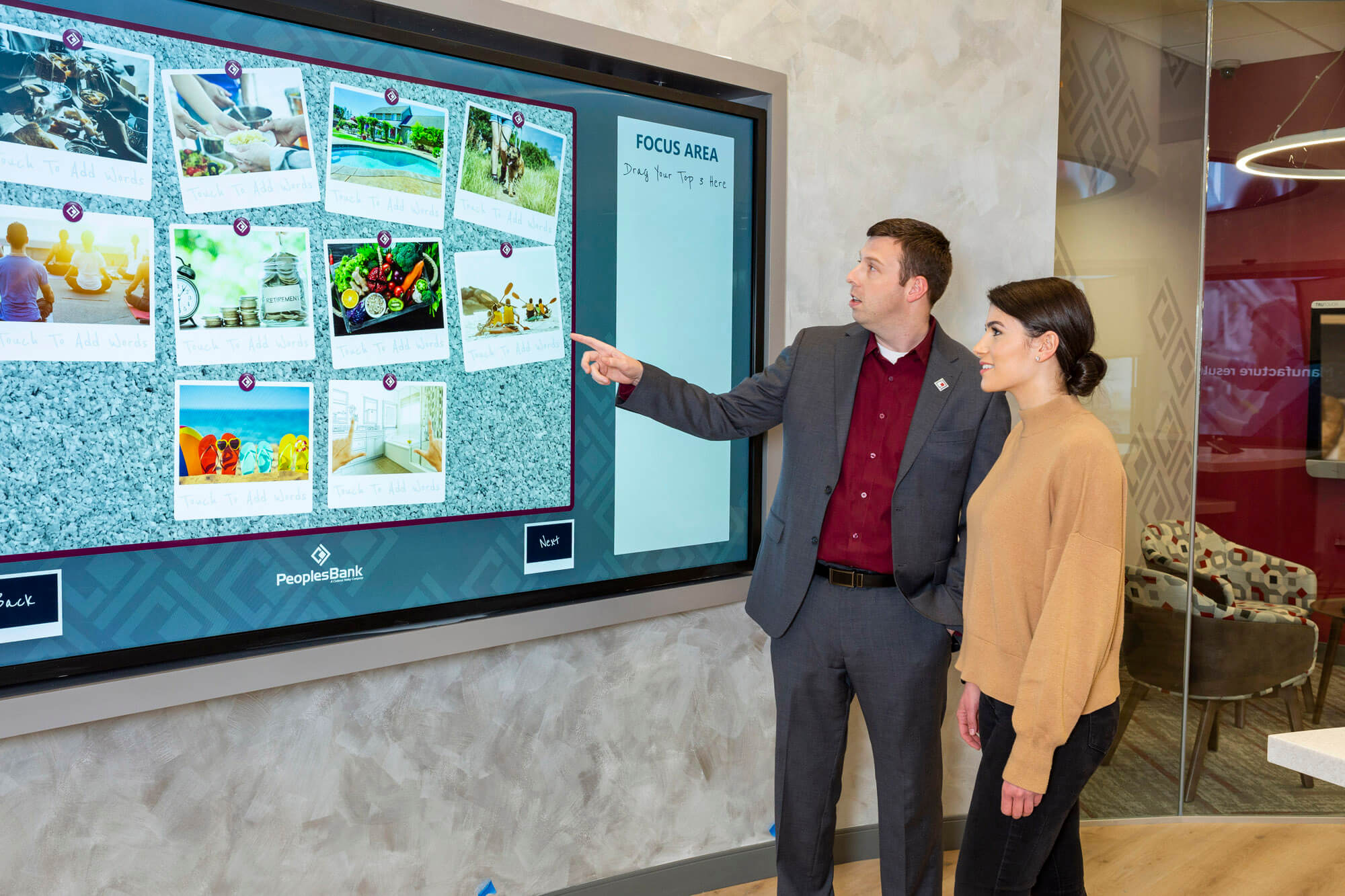 A man pointing to a large screen, showing a lady the information.