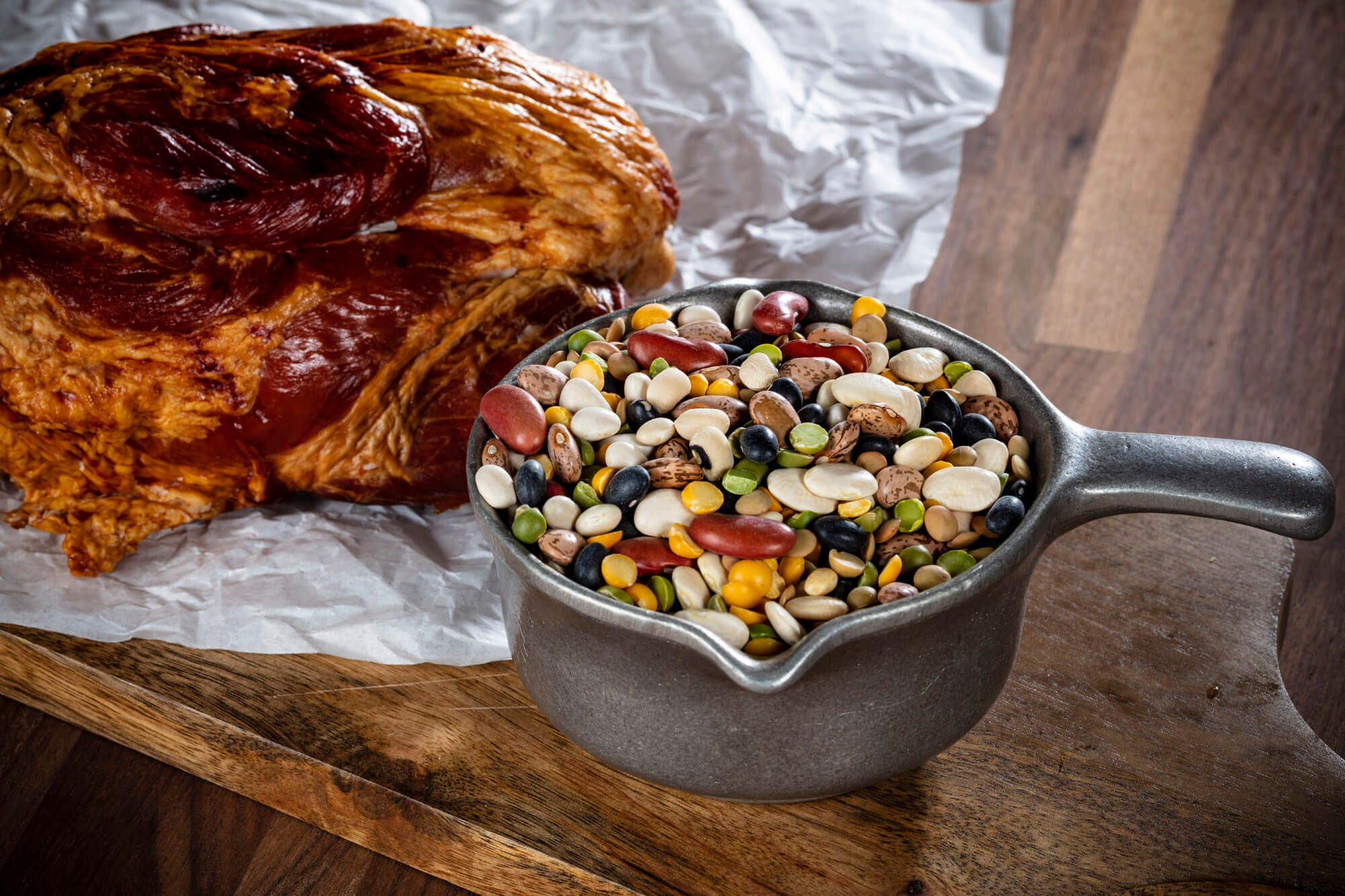 A steel bowl containing soup mix and a bread roll in the background.