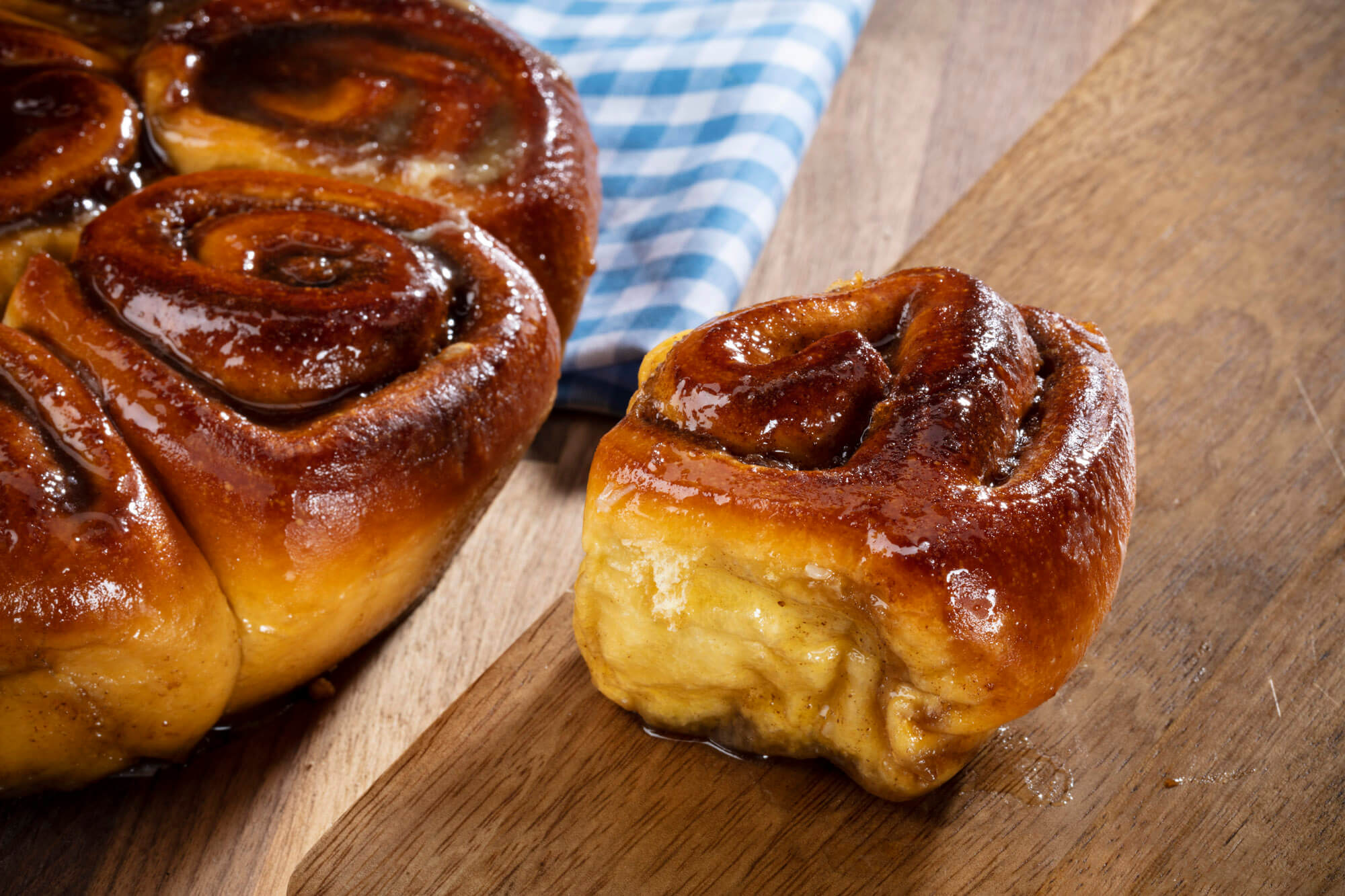 A large and small sticky bun on a wooden board.