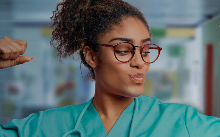 Woman in nurses clothing flexing her arm muscles.
