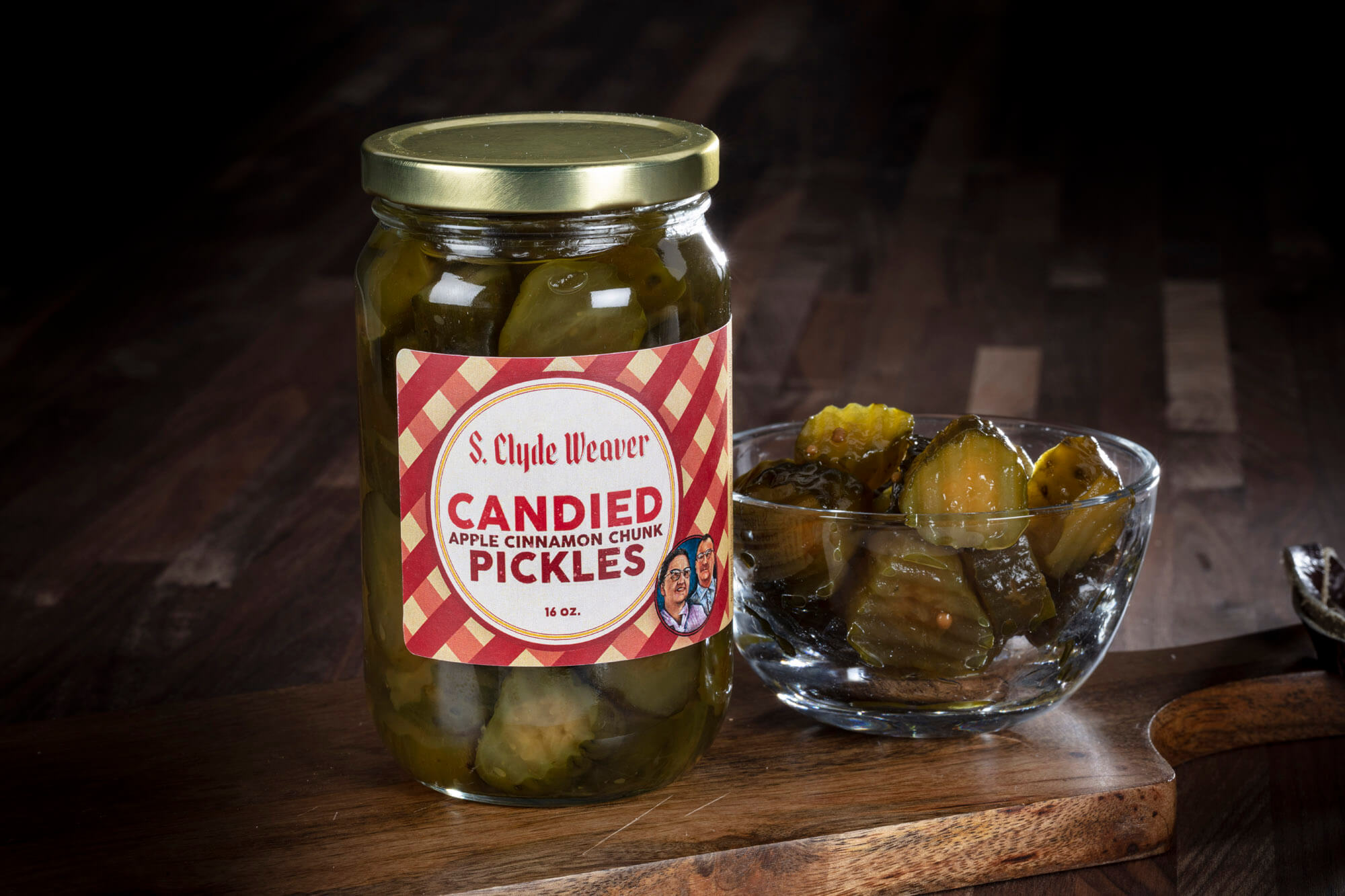 A jar of pickles and a small glass cup with some in next to it.