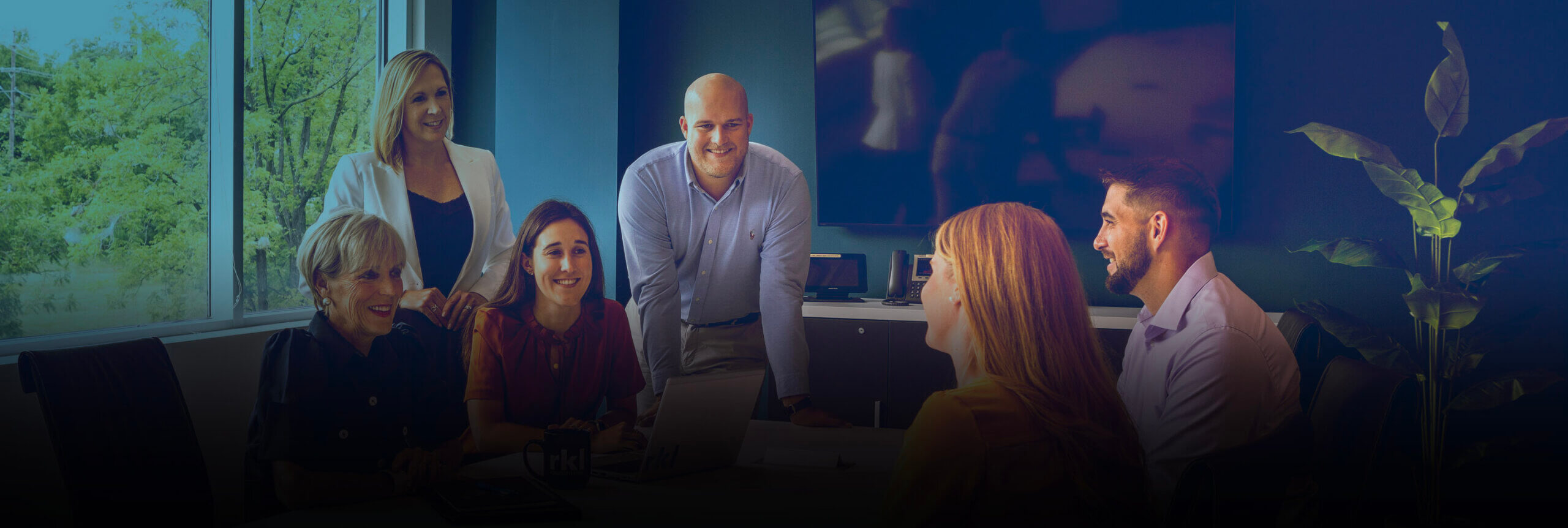 A group of six people meeting over an office desk.