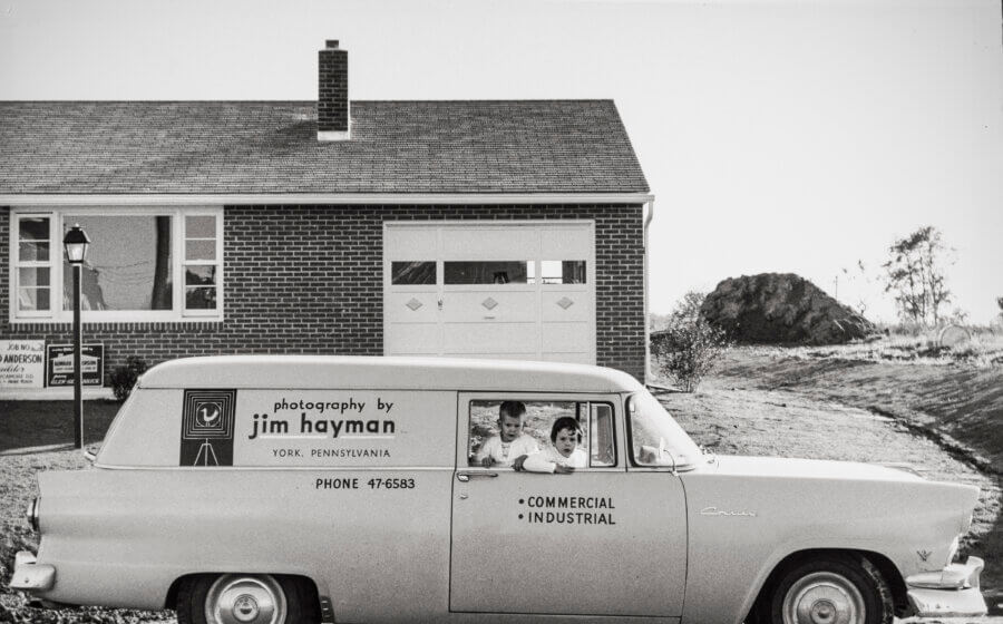 Old car from the 1950s with the original Hayman logo on the side and two kids in the front seat.