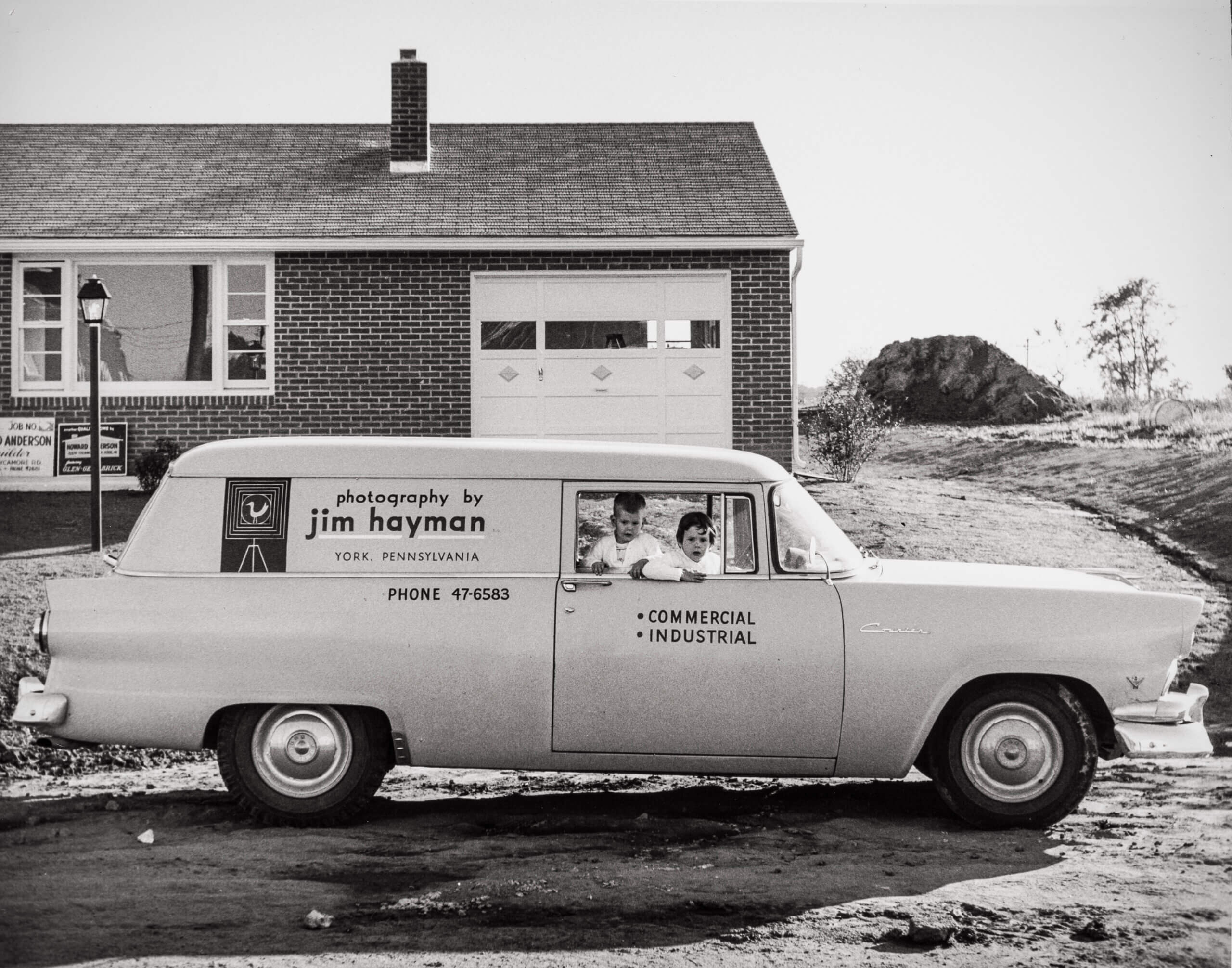 Old car from the 1950s with the original Hayman logo on the side and two kids in the front seat.