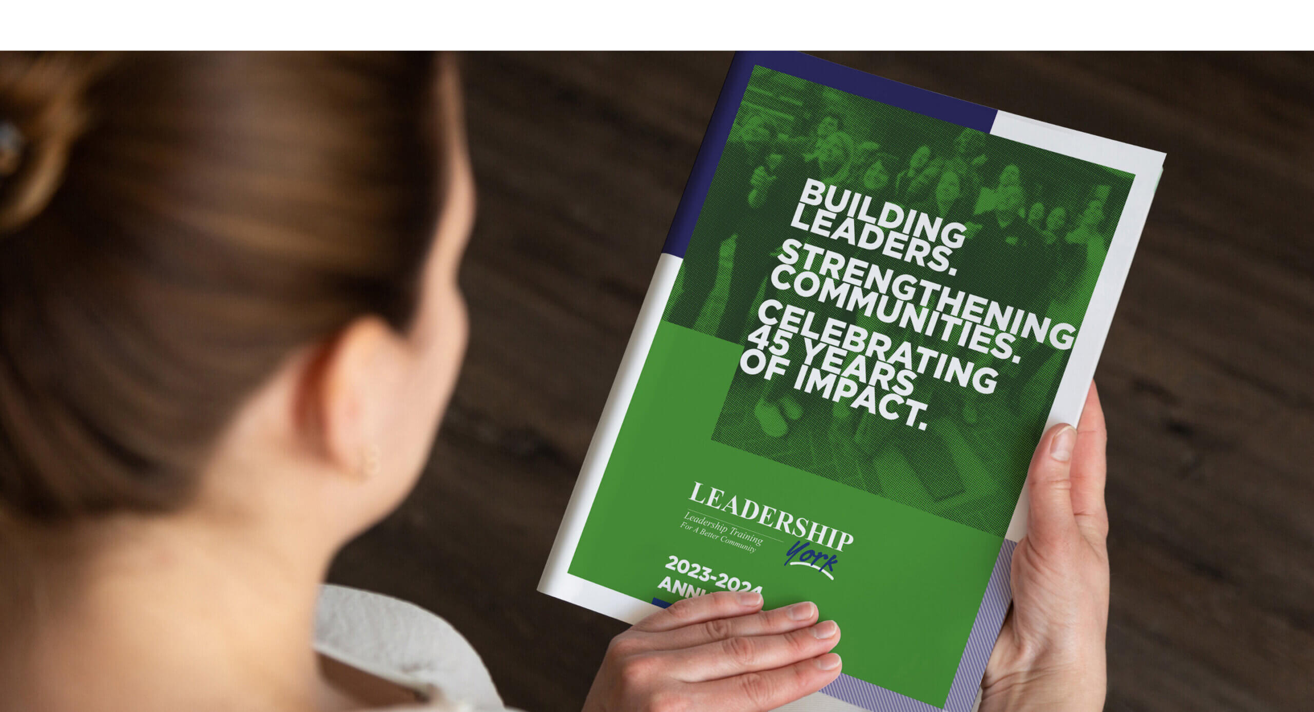 Woman looking at the front cover of the Leadership York Annual Report.